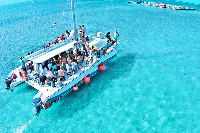 A catamaran full of people anchored in turquoise water